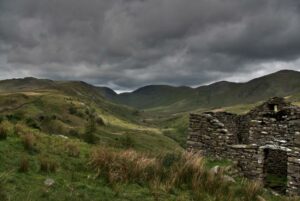 Rolling landscape with storm clouds in the background and stone bothy in the foreground