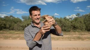 Nick Baker holds up an armadillo.