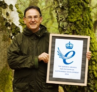 Nick Brown holds up a certificate of the Queens Award