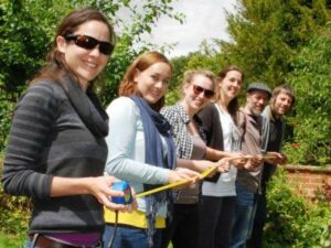 A row of World Land Trust staff hold up a tape measure.