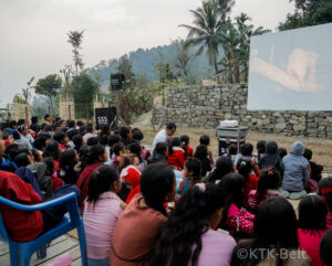 School children and community members watching a video of Pangolin conservation.