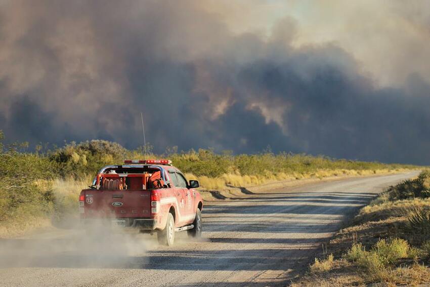 A vehicle on a road heading towards a wildfire.