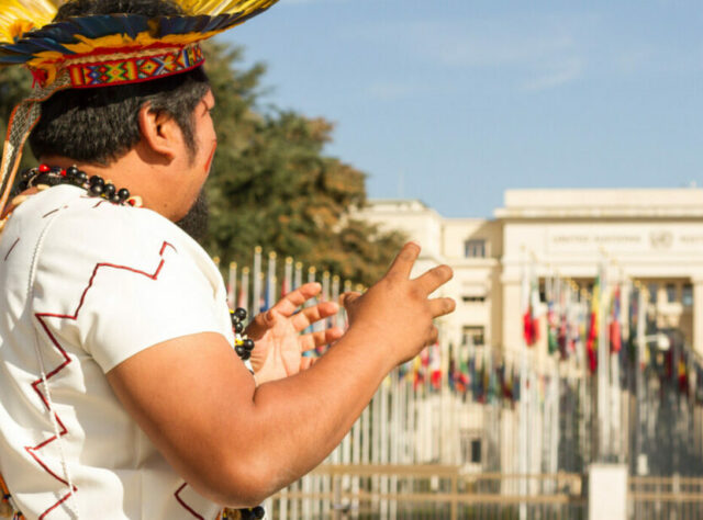 An indigenous spokesperson stands infront of the United Nations Offices in Geneva.