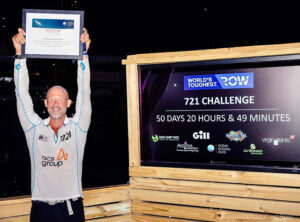 Nick Hollis holds aloft his certificate of completing the World's Toughest Row