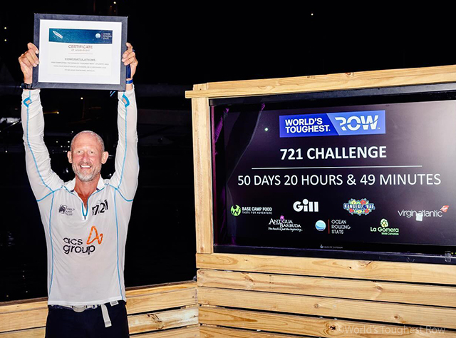 Nick Hollis holds aloft his certificate of completing the World's Toughest Row