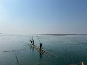 Villagers paddle across wetlands on a bamboo raft