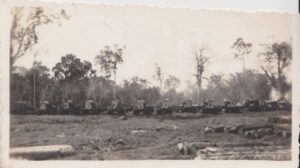 A sepia photograph of 16 tractors lined up during at Gallon Jug winter of 1945-1946.