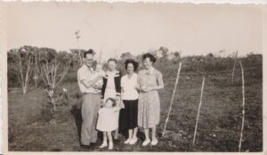 A sepia photo of Hilary Hunt in 1949 at 2 years old with her mum and dad, baby brother born December 1948, and grandmother (mother's mother) who was visiting from Bristol for several months