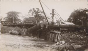 A sepia photograph of a log offloaded at Hill Bank, Belize, caught in mid-air as it's dropped into the lagoon for transportation to the coast.