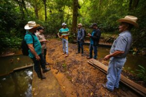 group of community members standing in discussion at a micro-basin in the Honduran forest.