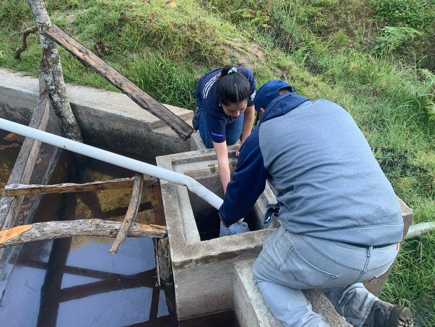 a community member and a forest ranger collecting water samples for quality analysis. 