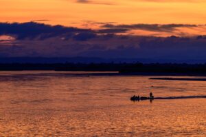 A sunset on the wetland, fishermen travelling through the golden waters.