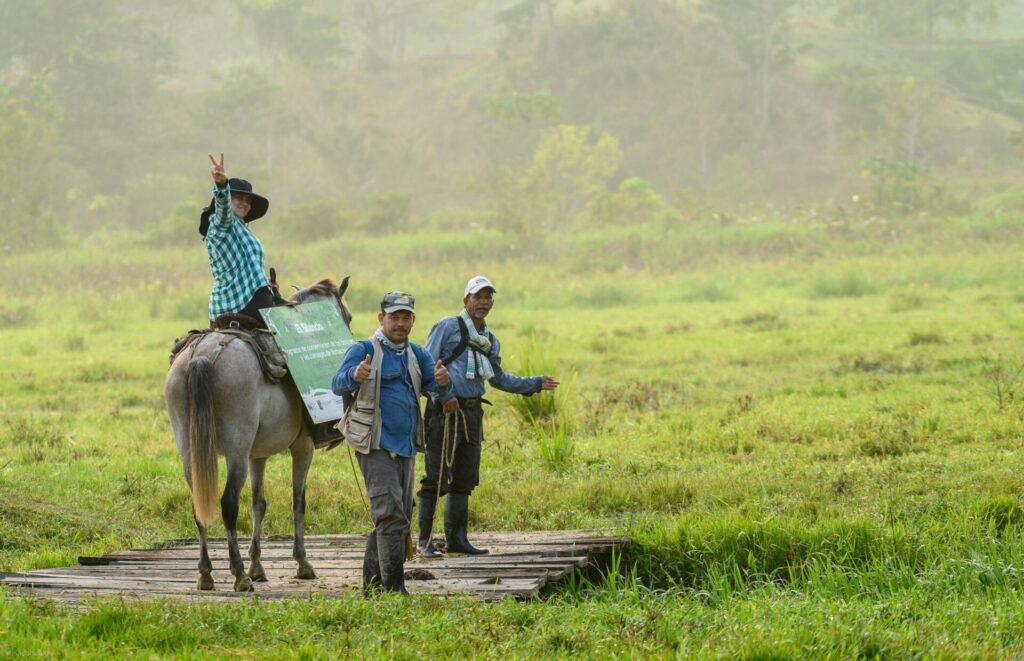 Several FBC team members in the field, one on horseback. Smiling towards camera.