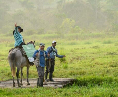 Several FBC team members in the field, one on horseback. Smiling towards camera.