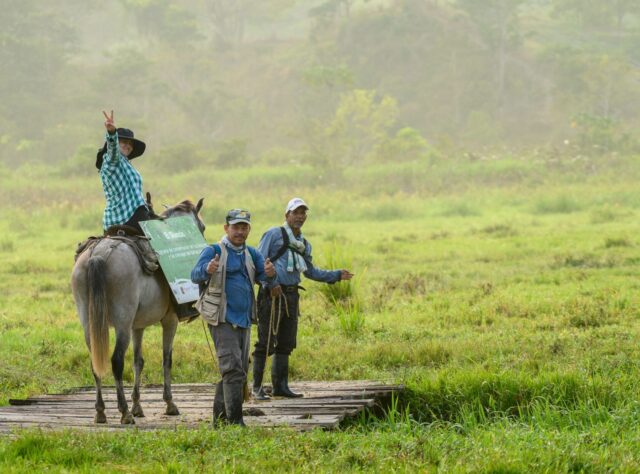 Several FBC team members in the field, one on horseback. Smiling towards camera.